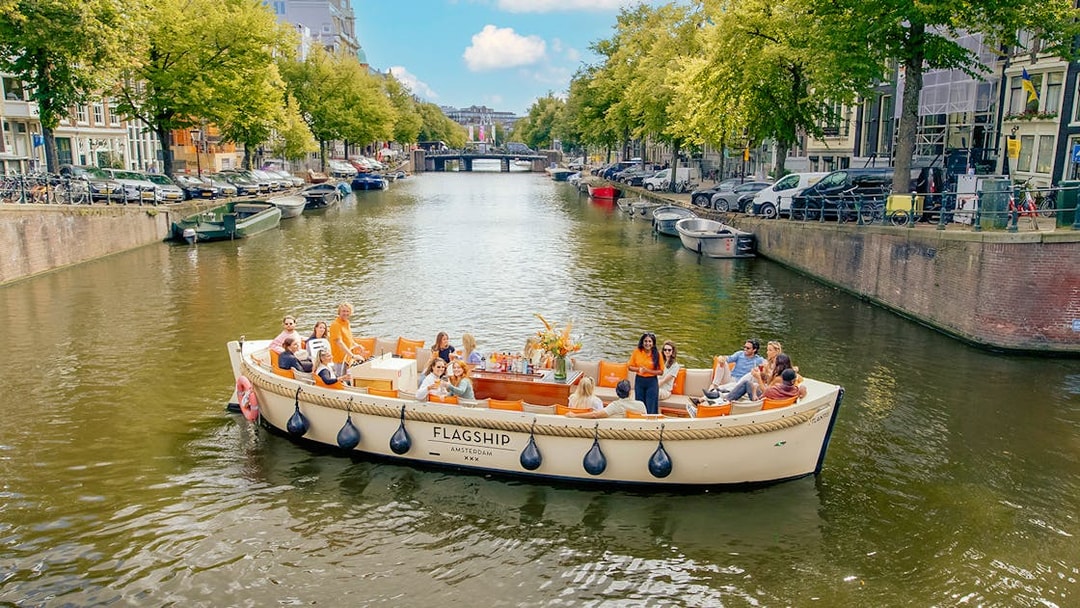 Luxury open boat cruise on Amsterdam canal with passengers enjoying the view.