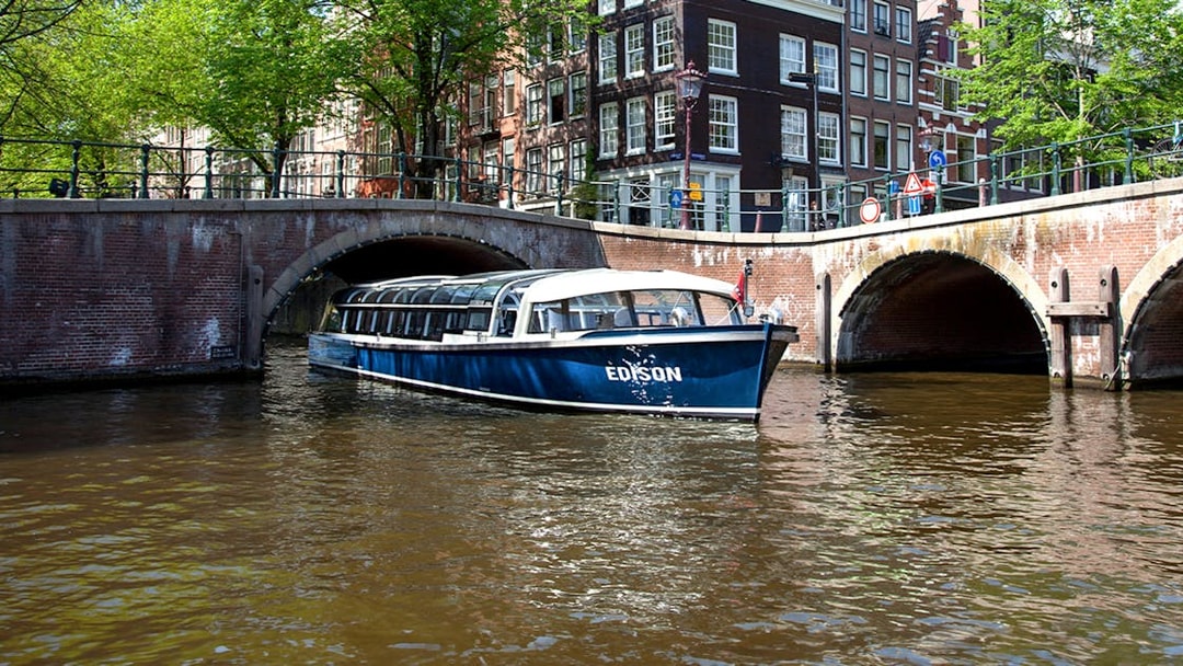Canal cruise boat passing under a bridge in Amsterdam.