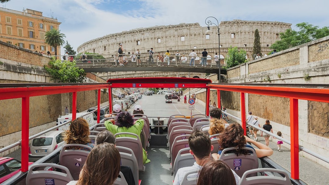 Open-top sightseeing bus approaching the Colosseum in Rome.
