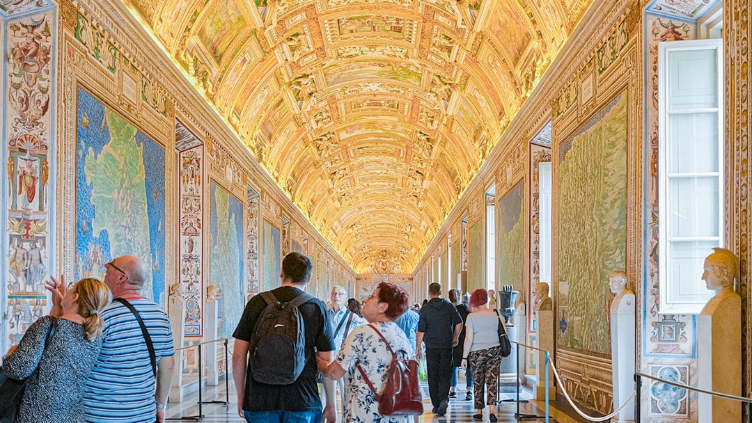 Visitors exploring the ornate Gallery of Maps at the Vatican Museum.