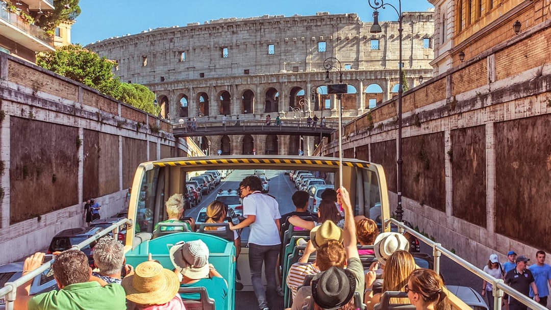 Tour guide interacting with tourists on a bus near the Colosseum in Rome.