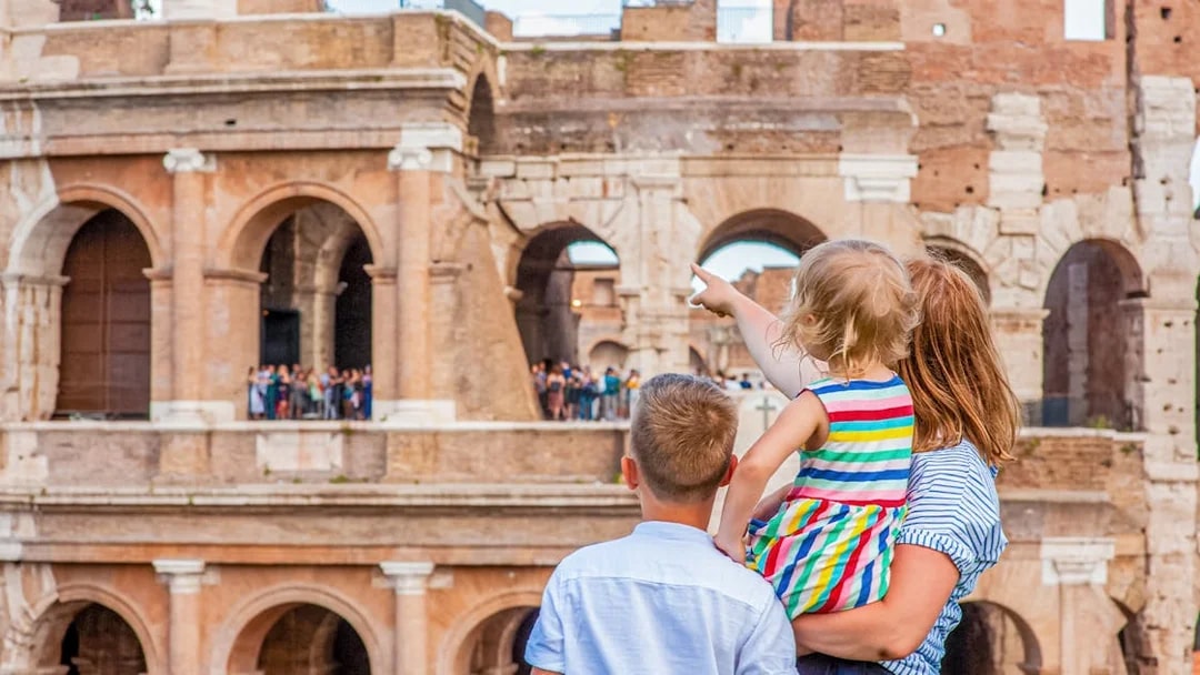 Family exploring the Colosseum in Rome, child pointing at ancient arches.