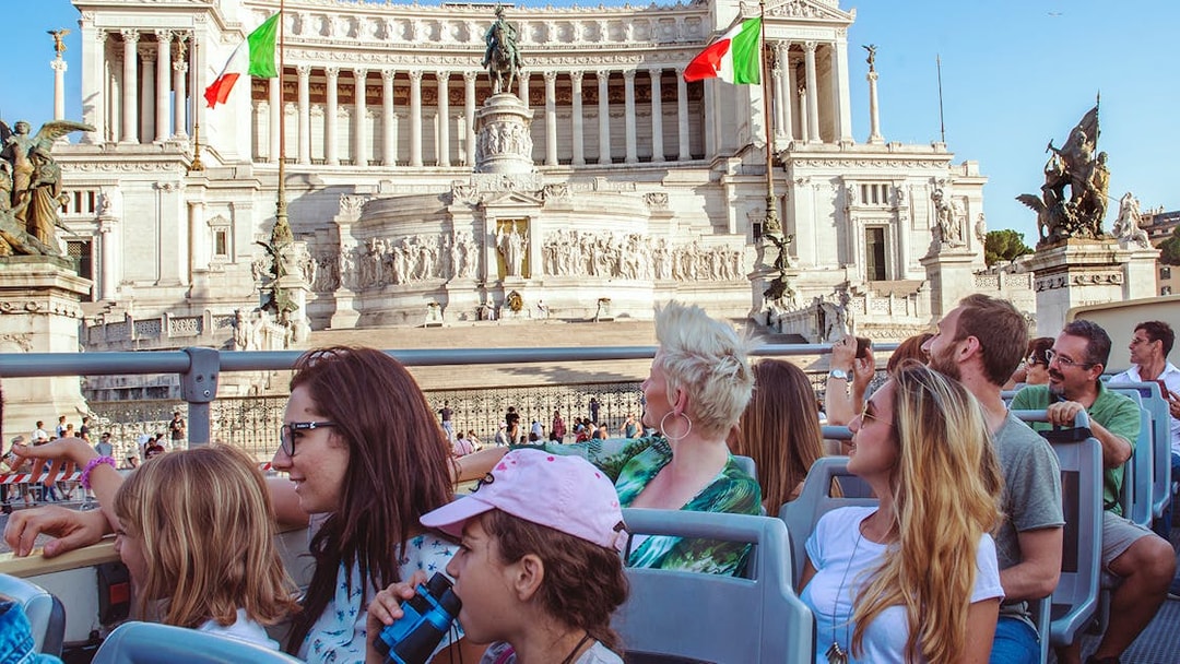 Tourists on a hop-on hop-off bus viewing the Altare della Patria in Rome.