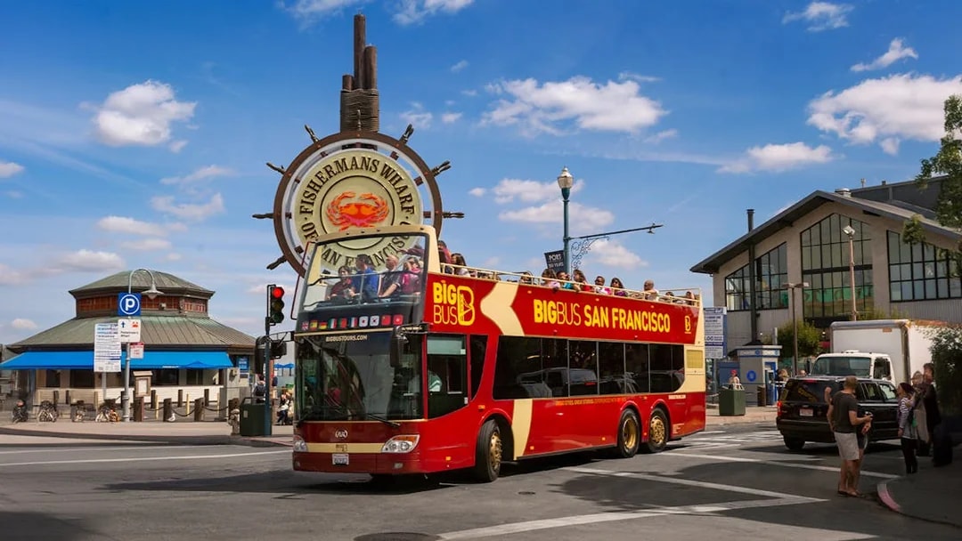 Big Bus tour at Fisherman's Wharf, San Francisco, with iconic sign in background.