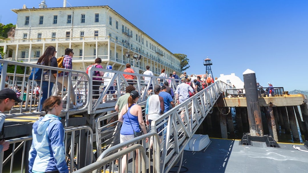 Visitors walking up a ramp to Alcatraz Island, San Francisco, with historic buildings in view.