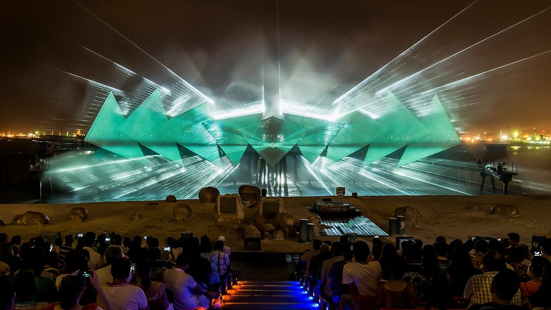 Wings of Time light show at Sentosa, Singapore, with audience watching vibrant projections.