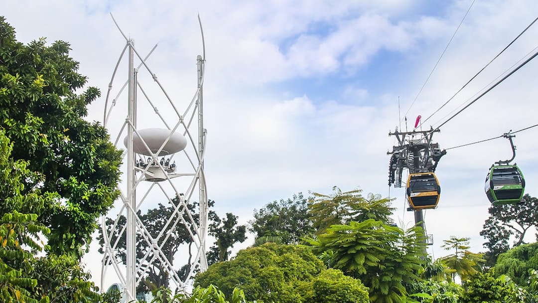 SkyHelix Sentosa and Singapore Cable Car over lush greenery.