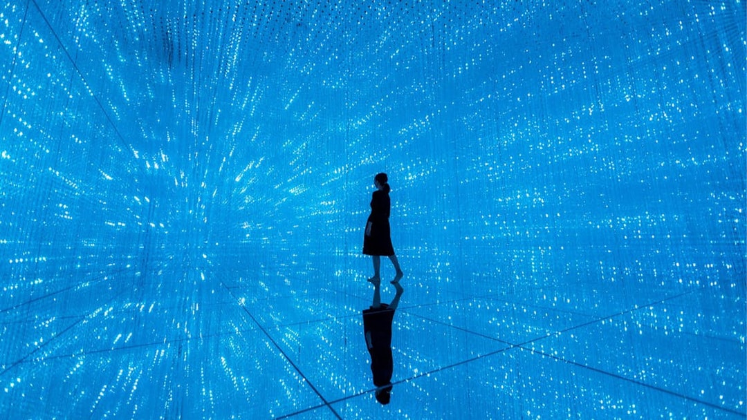 Person walking through digital light installation at TeamLab Planets Tokyo exhibit.