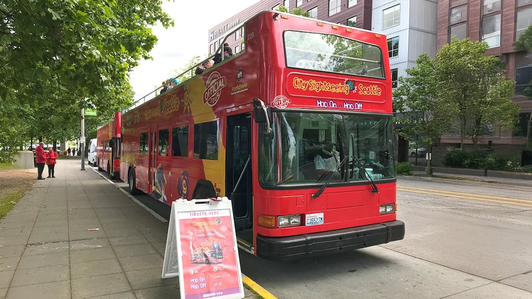 City Sightseeing bus at Seattle bus stop with ticket sign nearby.
