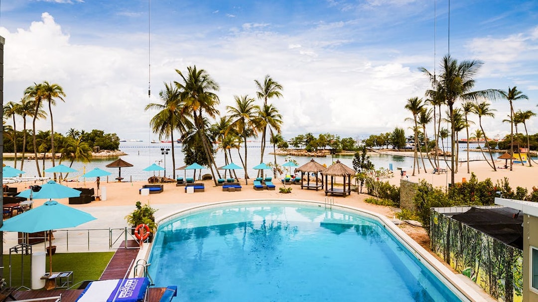 Sentosa beach view with pool and palm trees, Singapore.