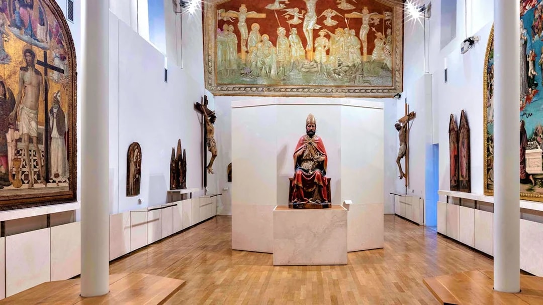 Museum of Brunello di Montalcino gallery with religious sculptures and frescoes.