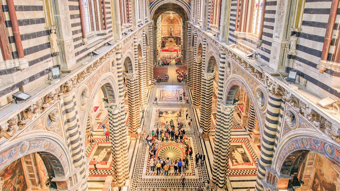 Siena Duomo interior with striped columns and visitors exploring the ornate architecture.