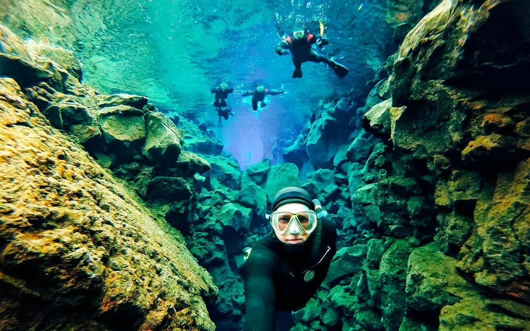 Snorkelers exploring the clear waters and rocky formations of Silfra in Iceland.