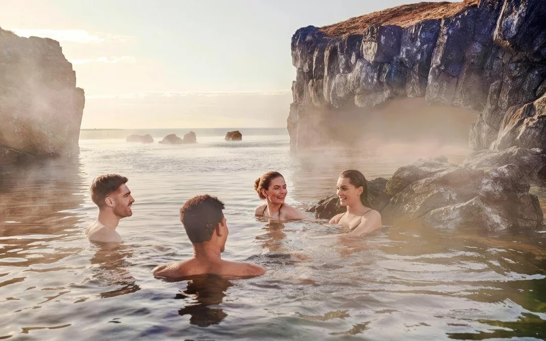 Guests enjoying geothermal waters at Sky Lagoon, Iceland, surrounded by rocky cliffs.