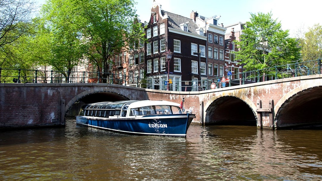 Canal boat under bridge in Amsterdam near STRAAT Museum.