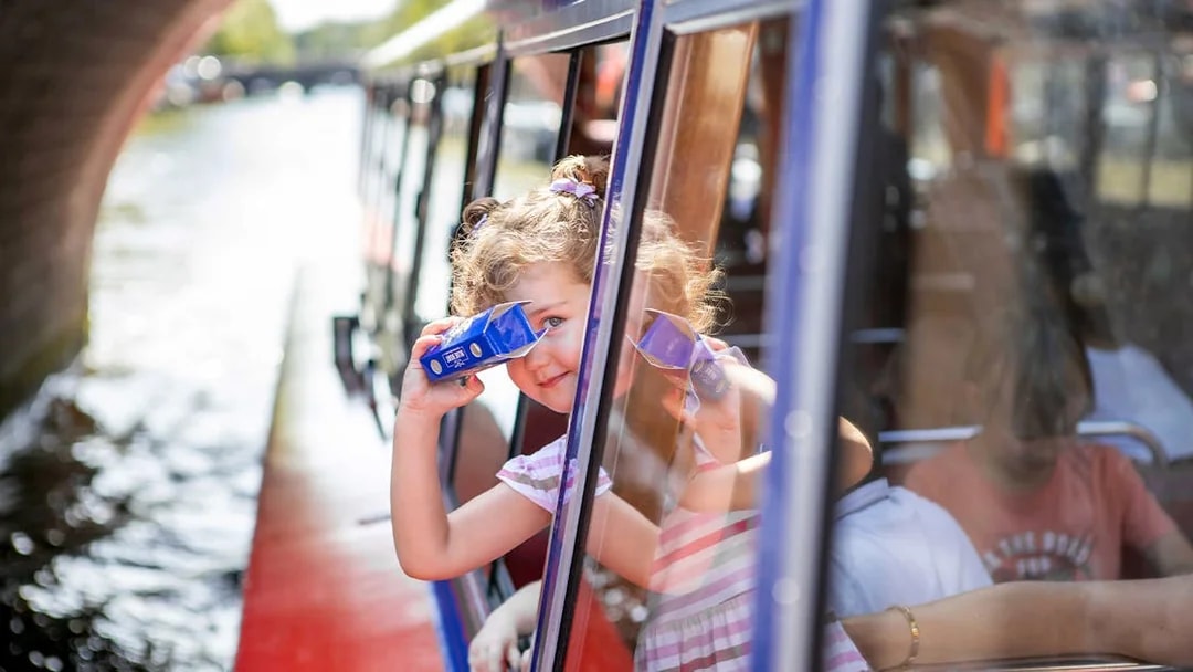 Child looking through binoculars on Amsterdam canal cruise.