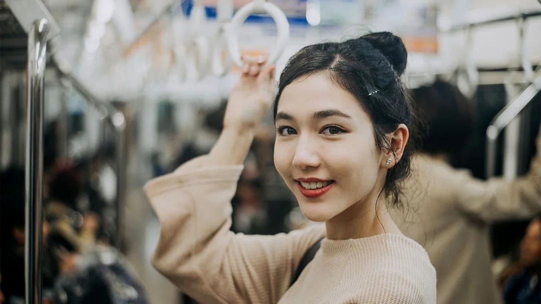 Woman holding onto a handrail in Tokyo subway.