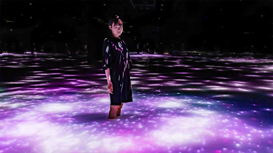 Person standing in illuminated water at teamLab Planets Tokyo exhibit.