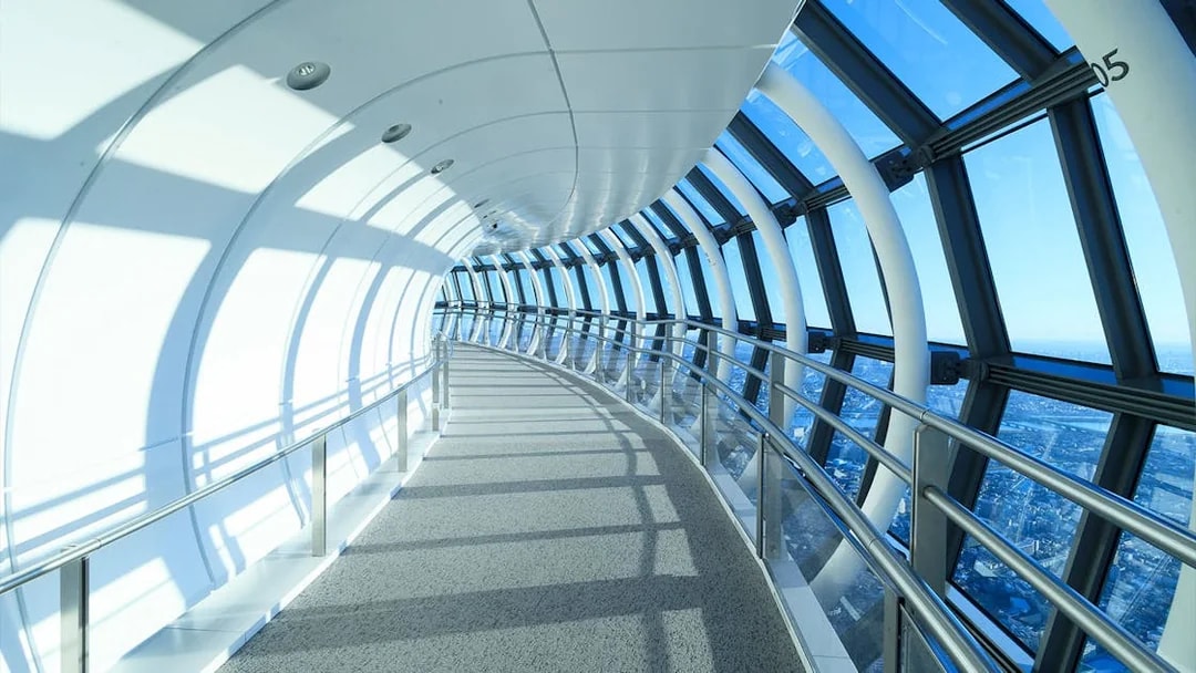Curved glass corridor at SkyTree Observation Deck, Tokyo, with city view.