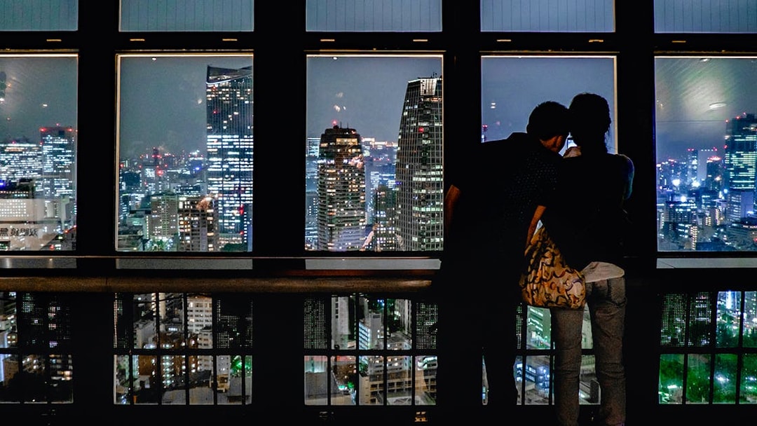 Couple enjoying Tokyo cityscape at night from Tokyo Tower observation deck.
