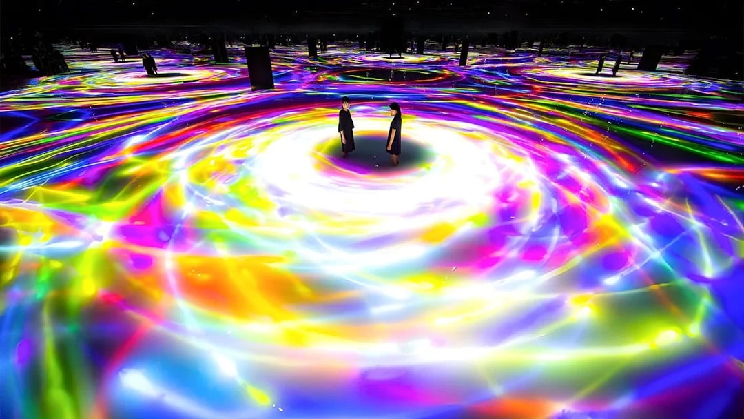 Visitors standing in colorful digital art installation at TeamLab Planets, Tokyo.