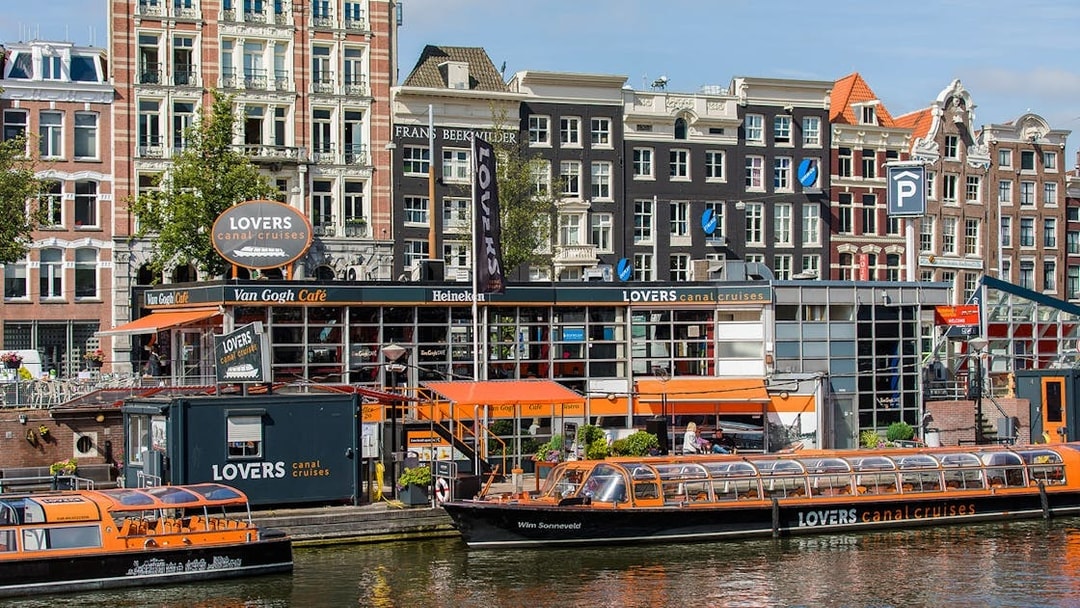 Canal cruise boats docked in front of Van Gogh Café in Amsterdam downtown.