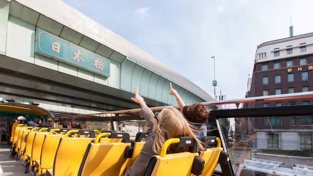 Tourists on Sky Hop bus pointing at Nihonbashi bridge in Tokyo.