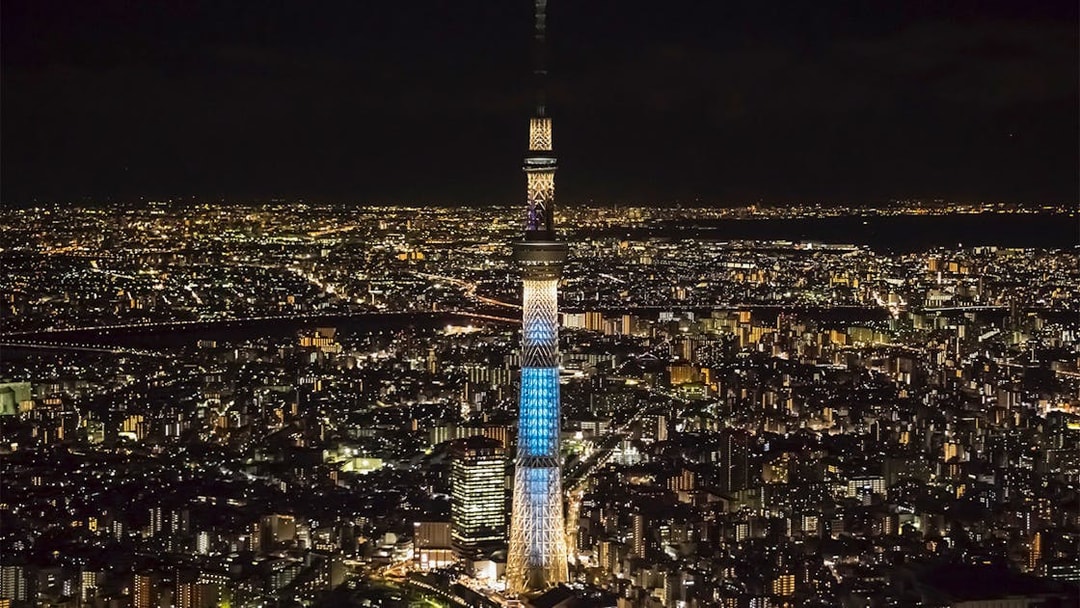 Tokyo Skytree illuminated at night, surrounded by city lights.