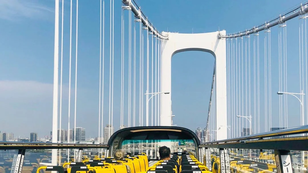 Open-top bus crossing Rainbow Bridge in Tokyo.