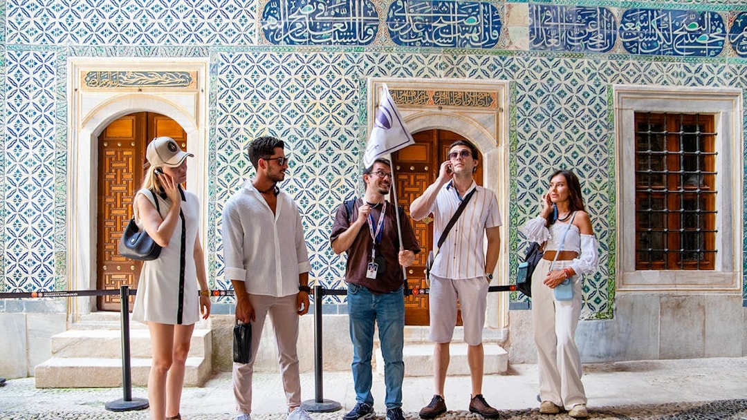 Tour group with guide at Topkapi Palace Museum, Istanbul, near ornate tiled wall.