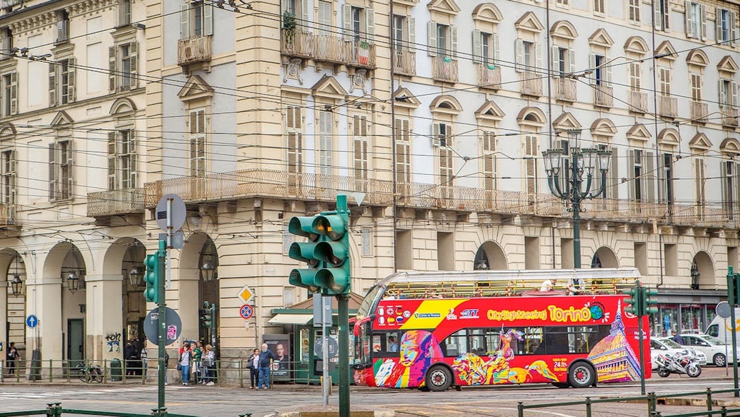 Turin hop-on hop-off bus passing historic building near Lavazza Museum.