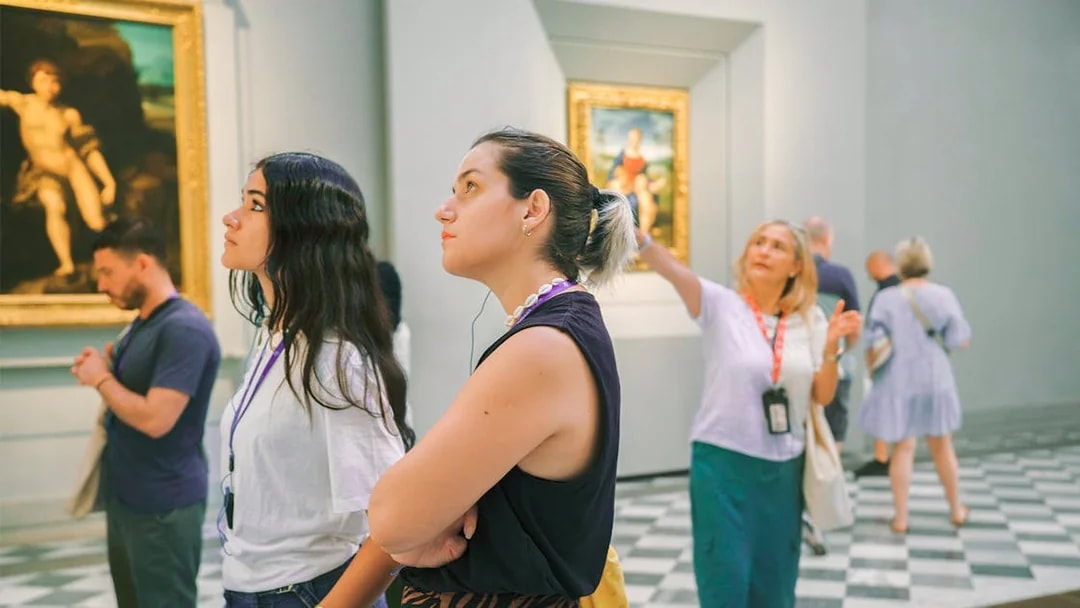 Woman admiring artwork in a gallery with others observing nearby.