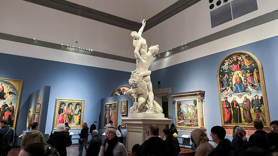 Accademia Gallery visitors viewing Renaissance paintings and a prominent sculpture.