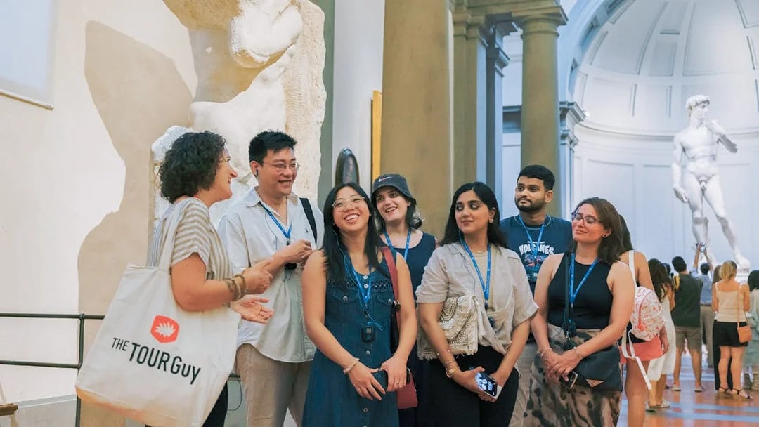 Group tour with guide discussing art in a gallery with sculptures in Florence.