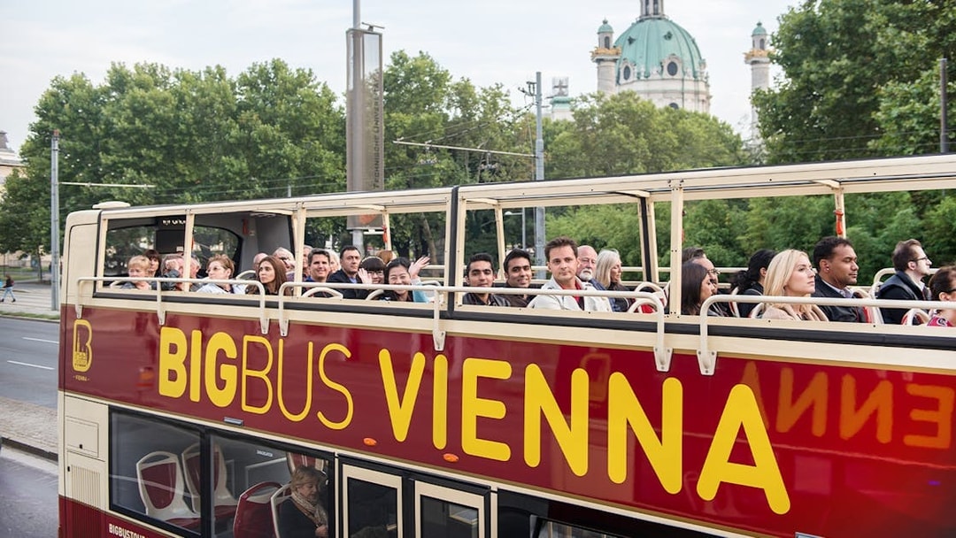 Tourists on Big Bus Vienna with St. Charles Church in the background.