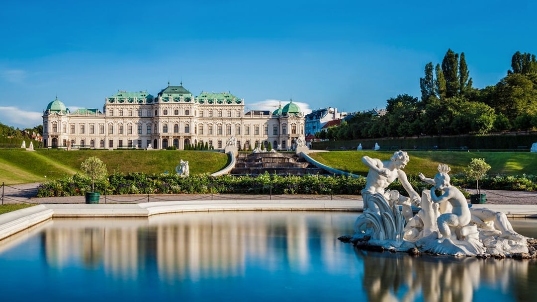 Statues in the gardens of Upper Belvedere Palace, Vienna, with palace in background.