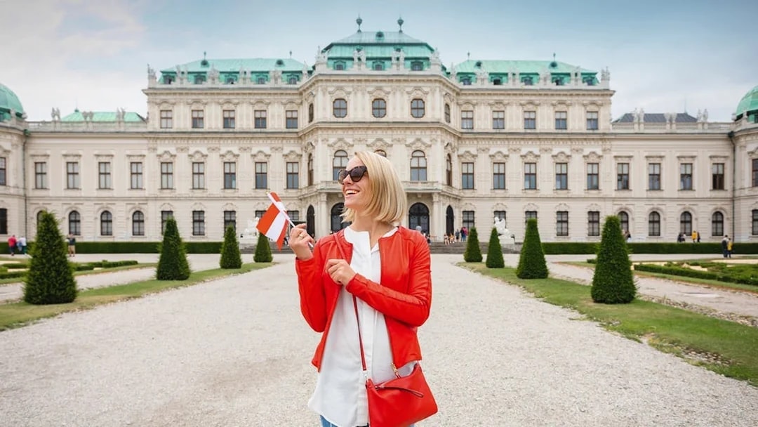 Woman holding a flag in front of Upper Belvedere Palace on a guided tour in Vienna.