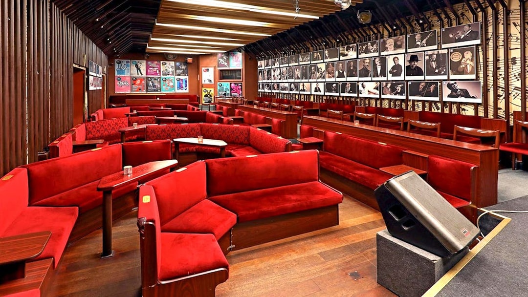 Reduta Jazz Club interior with red seating and musician portraits on walls.