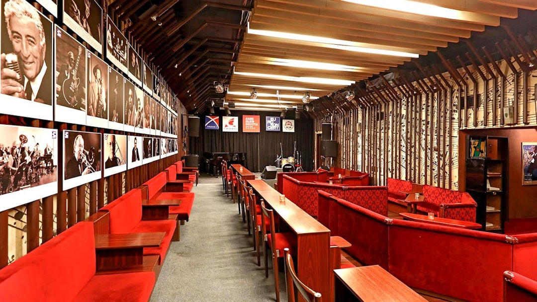Interior seating and stage at Reduta Jazz Club, Prague, with jazz musician portraits on the wall.