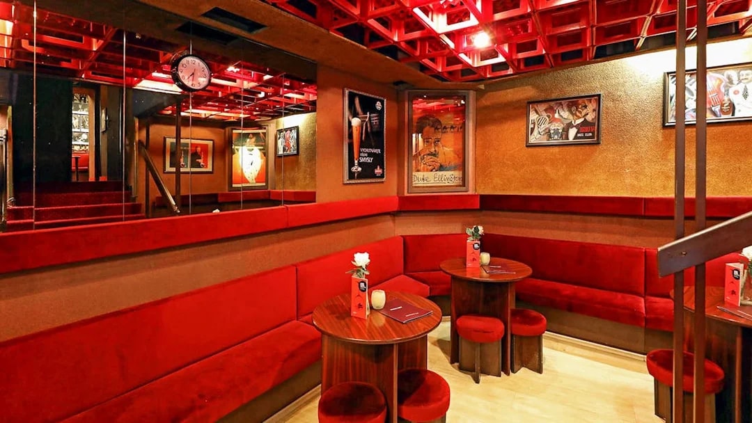 Interior seating area at Reduta Jazz Club with red velvet benches and jazz posters.