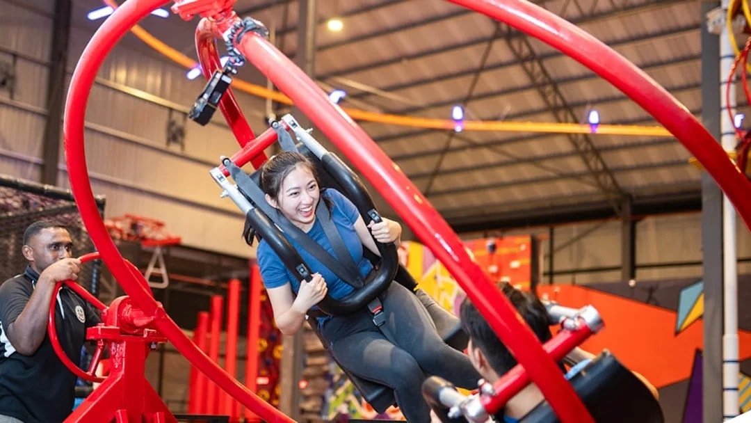 Woman enjoying a spinning ride at an indoor adventure park.