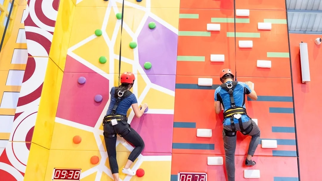 Man and woman climbing colorful indoor rock wall.