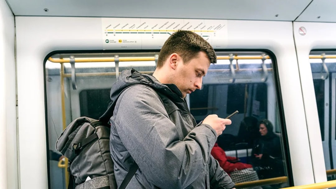 Man using phone on Copenhagen metro with city map above.