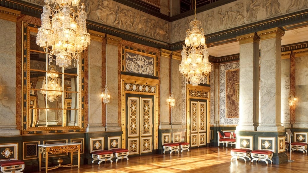 Interior of a grand hall in Copenhagen with ornate chandeliers and decorative walls.