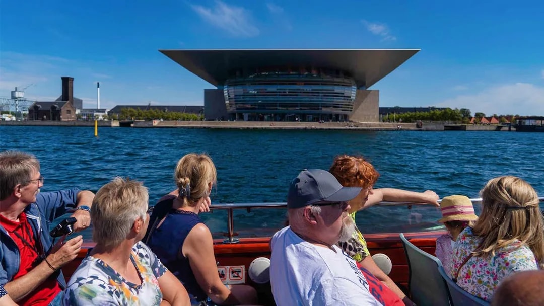Tourists on a boat viewing the Copenhagen Opera House from Ved Stranden.