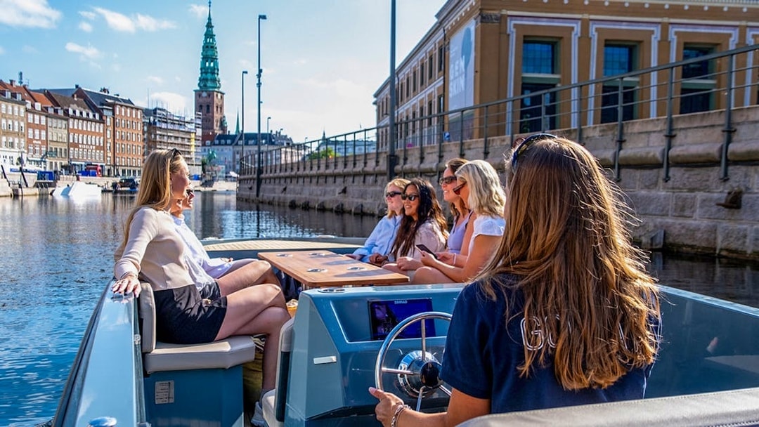 Guests on a boat tour in Copenhagen harbor, viewing city landmarks.