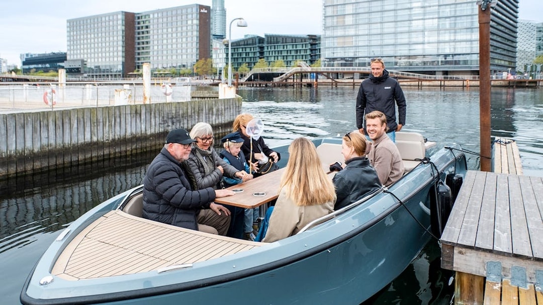 Guests on electric boat tour in Copenhagen with captain pedaling.