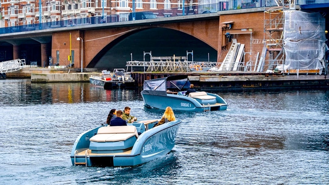 Harbour tour boat with guests in Copenhagen passing colorful waterfront buildings.