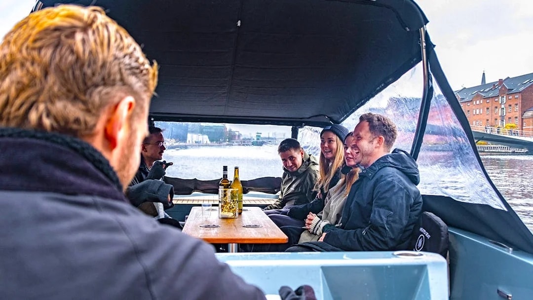 Guests on an electric boat enjoying a small group canal cruise in a city setting.