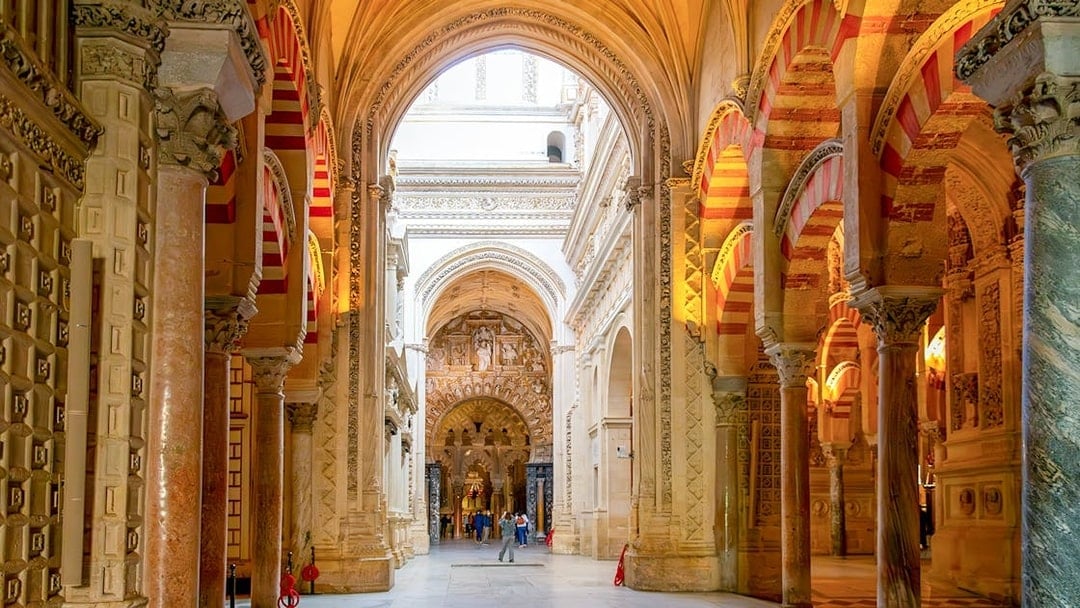 Visitors exploring the arches and columns inside Cordoba Mosque-Cathedral.